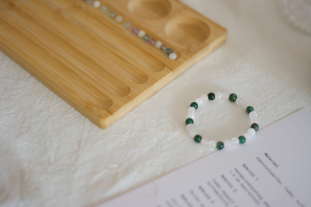 Selbstgemachtes Armband aus Natursteinperlen neben dem Perlenbrett